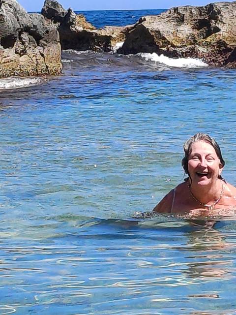       Person swimming in clear blue water, laughing.
  