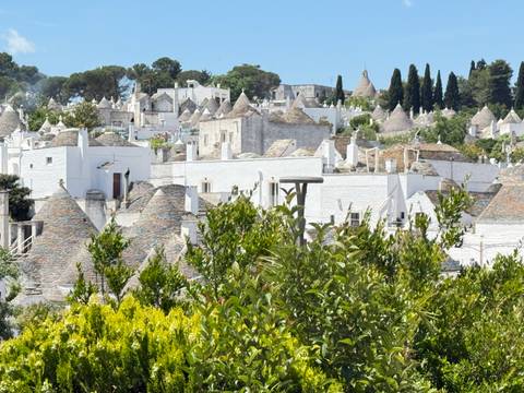       Traditional trulli houses under a clear blue sky.
  