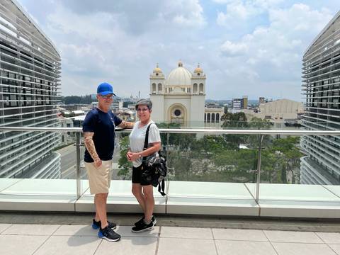 Couple posing in front of a large church with city skyline.