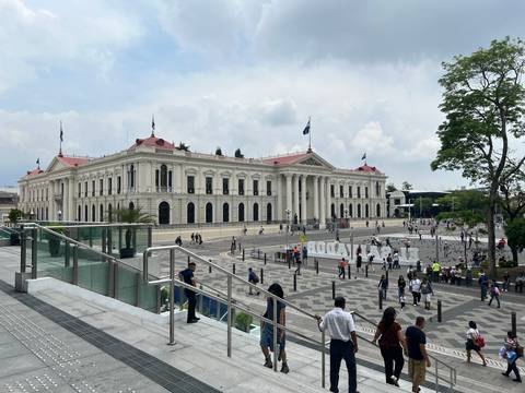 Large governmental building with flags and people in front.