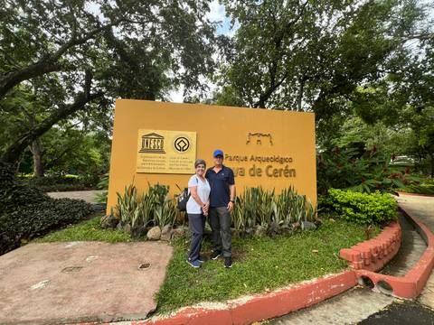       Two people in front of a sign for Joya de Ceren.
  