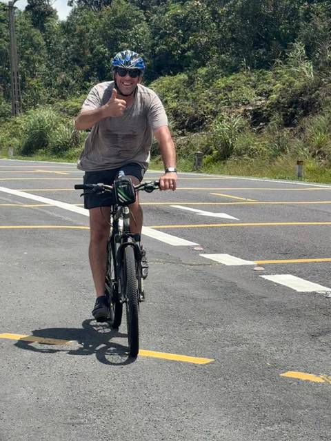       Man biking on the road with white markings.
  