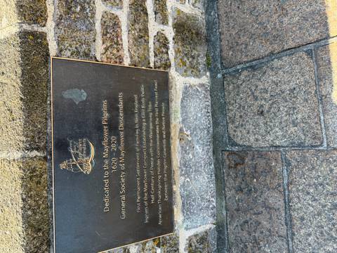Plaque dedicated to the Mayflower Pilgrims on a stone pavement.
