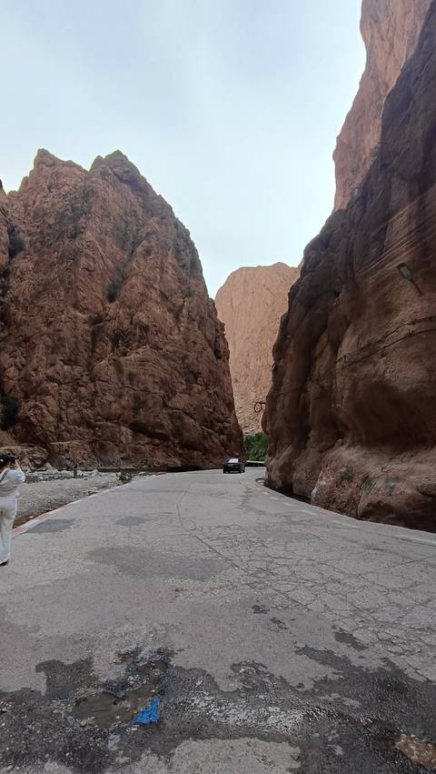       A car driving through a narrow canyon with high cliffs.
  