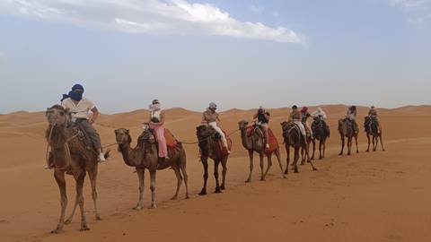       A group of people riding camels in the desert.
  