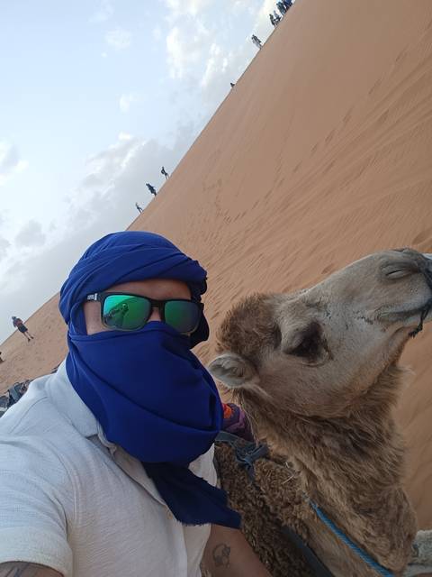       A person in the desert with a camel.
  