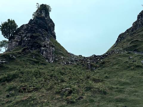 A rugged hill with scattered rocks and greenery.