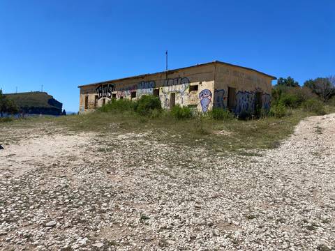 An abandoned building with graffiti near a shoreline.