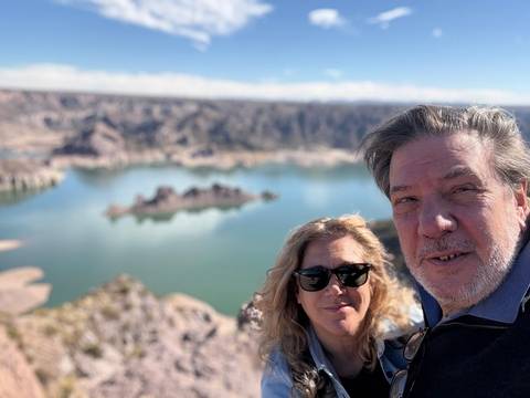 Couple selfie with a backdrop of a vast lake and rocky landscape.