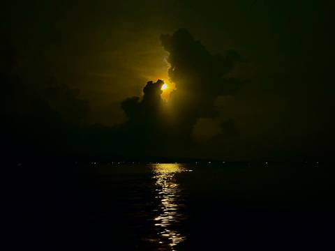       Silhouette of a dramatic cloud formation against a setting sun over water.
  