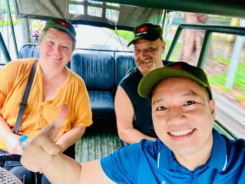 Group of people smiling in a vehicle with green surroundings.