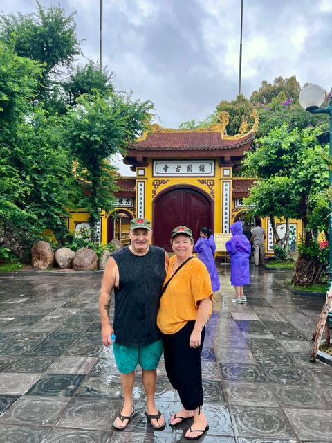 Couple posing in front of an ornate temple structure with others around.