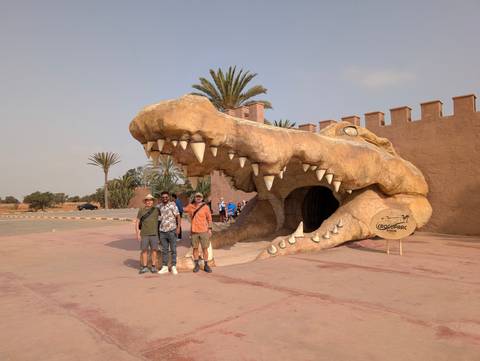 Group of people posing beside a large crocodile statue.