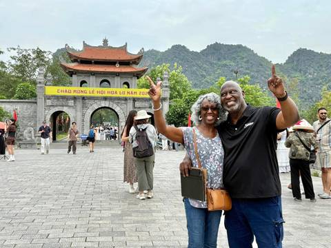       Couple posing in front of a historic gate with mountains in the background.
  