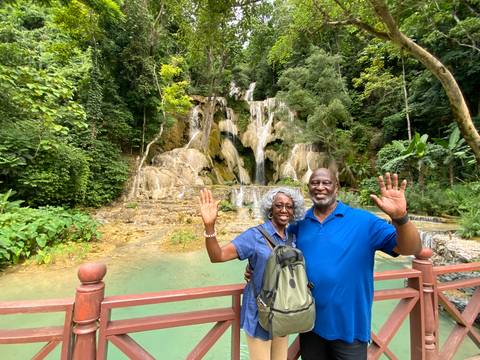      Couple posing in front of a waterfall in a lush landscape.
  