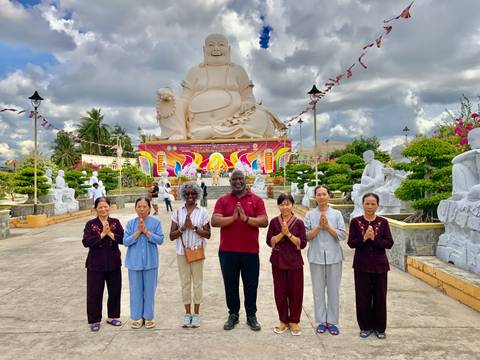       Group of people standing in front of a large Buddha statue.
  