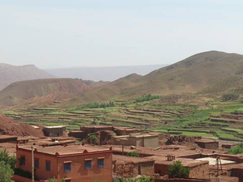 Mountainous landscape with terraced fields and clay buildings.