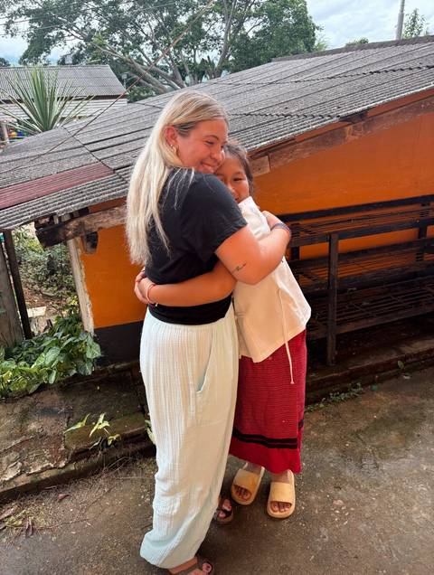 Two people hugging warmly outside a building.