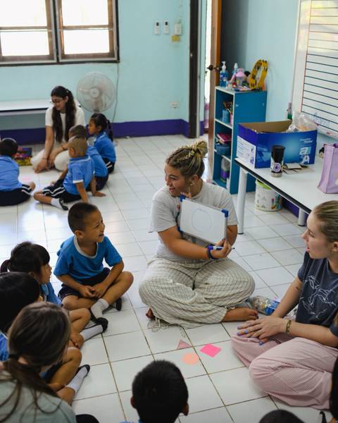 A group of people in a classroom, one woman holding a whiteboard.