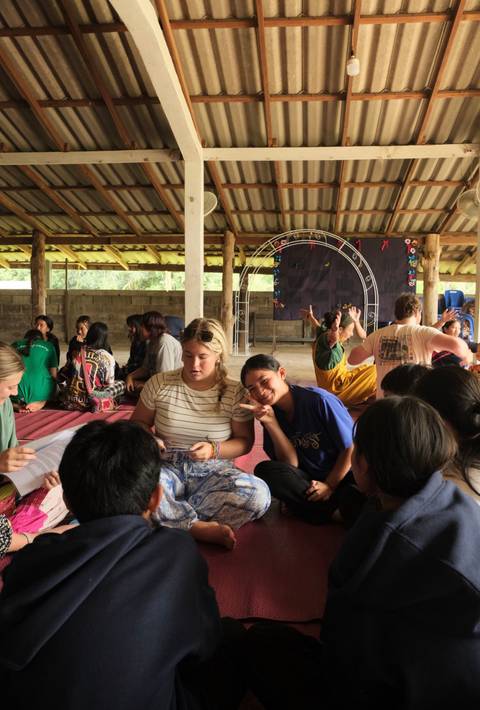 A group of people sitting together, engaged in an activity on the floor.