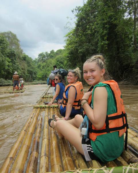 People rafting on a bamboo raft along a river.