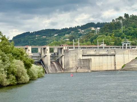 Dam with water flowing and trees in the background.