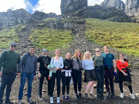 Group of people hiking with mountainous terrain in the background.