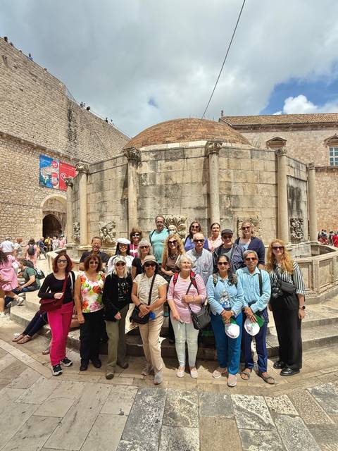 Group of people posing in front of an ancient stone fountain.