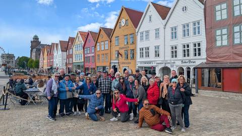       Group of people posing in front of historic colorful buildings.
  