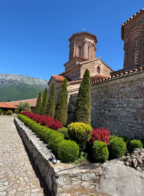 View of a historic stone church with gardens.
