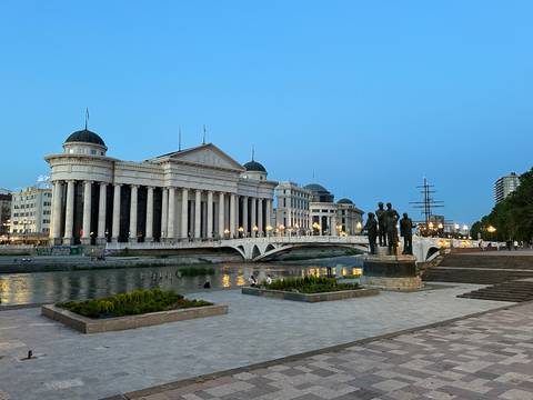 Panoramic view of a grand building with river and statues.