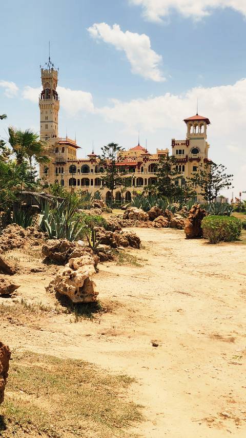 Historic palace surrounded by gardens and rocky grounds.
