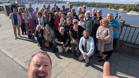       Large group of people posing by a body of water.
  