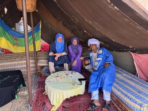 Three people in traditional Berber tent with colorful patterns.