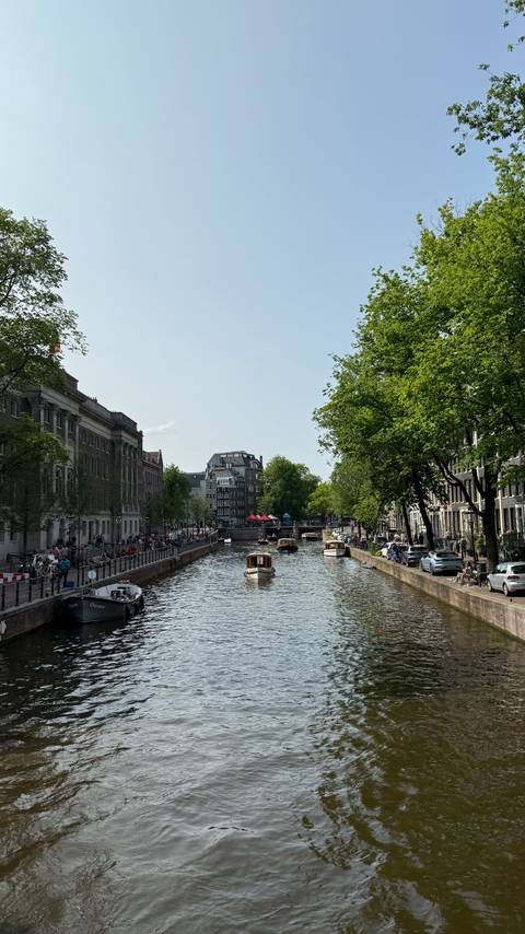 Canal view in Amsterdam with boats and people.
