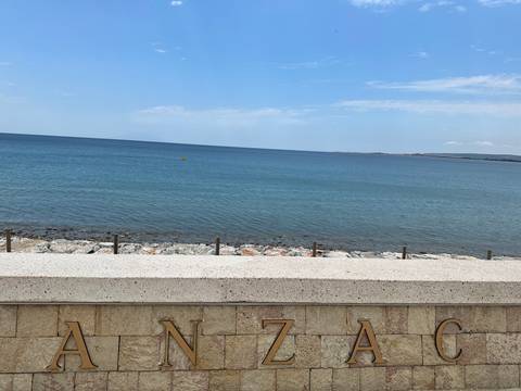Coastal view from a promenade with a sign.