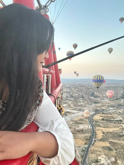 Person in a hot air balloon with other balloons in the distance.