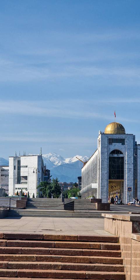       Cityscape with modern buildings and mountains in the background.
  