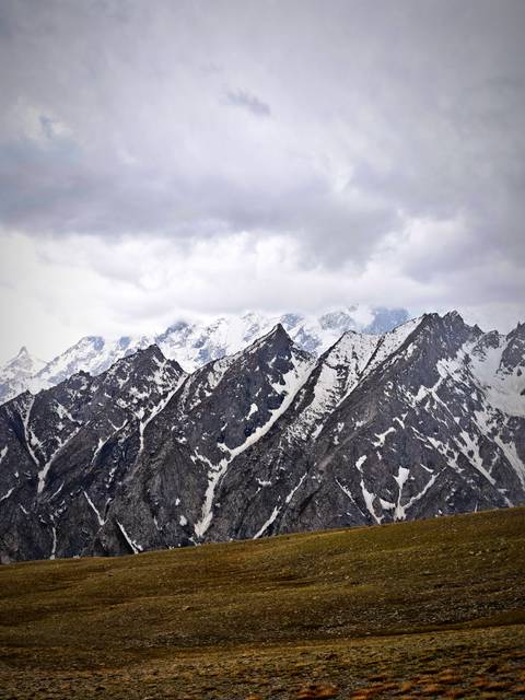 Snow-covered jagged mountain peaks under a cloudy sky.