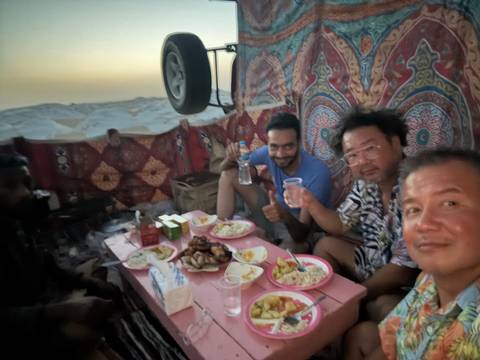       Group enjoying a meal in a tent setting.
  
