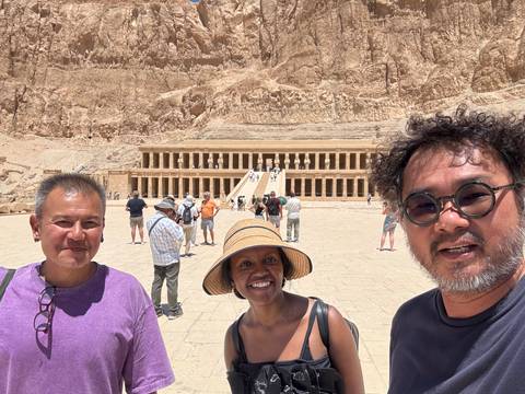       Tourists in front of a temple entrance in a desert landscape.
  
