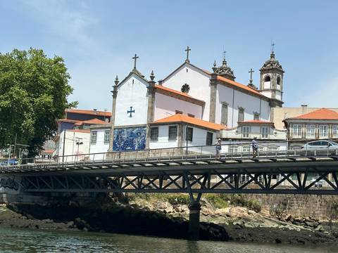       Riverbank view with a tiled-roof church and blue azulejos.
  