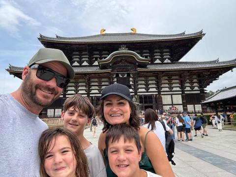 Family smiling in front of a large traditional wooden building.