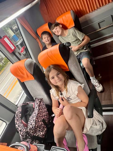 Child sitting inside a bus looking at the camera.