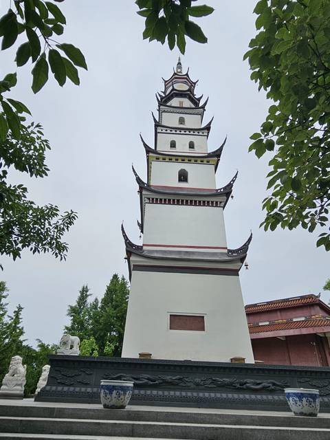 Tall white pagoda in a park setting.