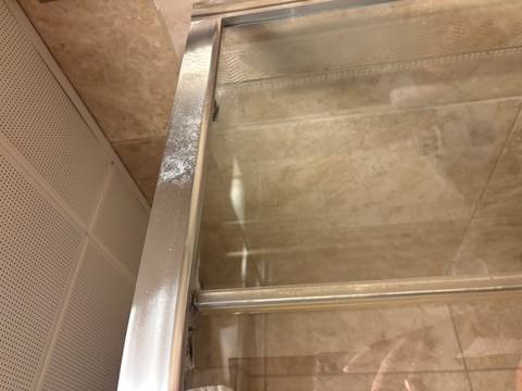 Close-up of a glass shower door with stains.