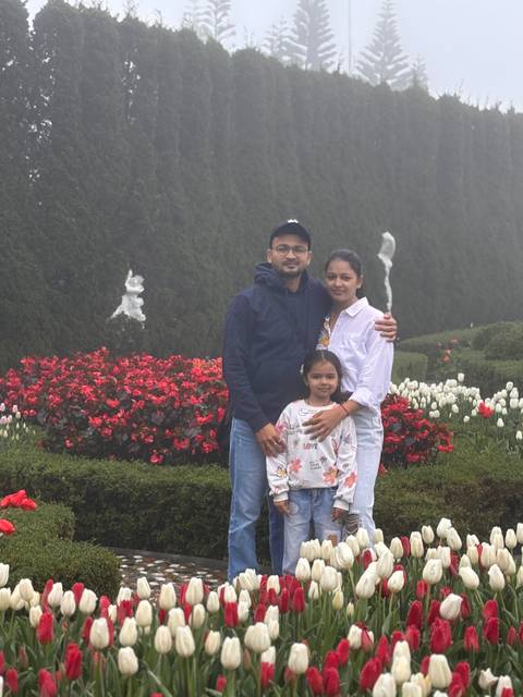       Family posing in a garden with vibrant flowers.
  