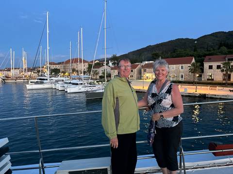 Couple posing in front of a marina with yachts and buildings.