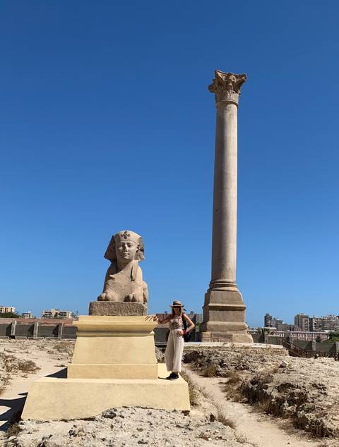       Sphinx and ancient column with clear blue sky.
  