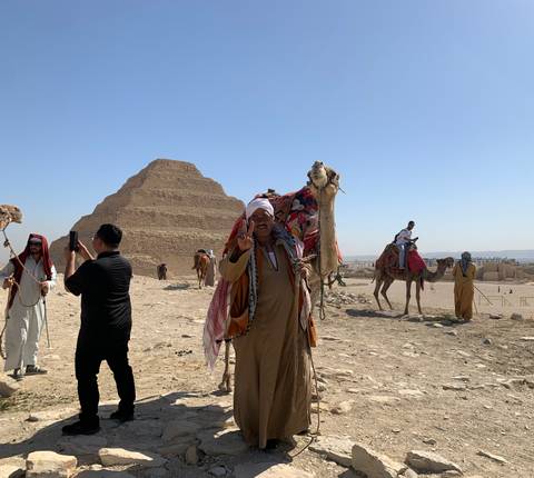 Camel ride near a pyramid in a desert landscape.
